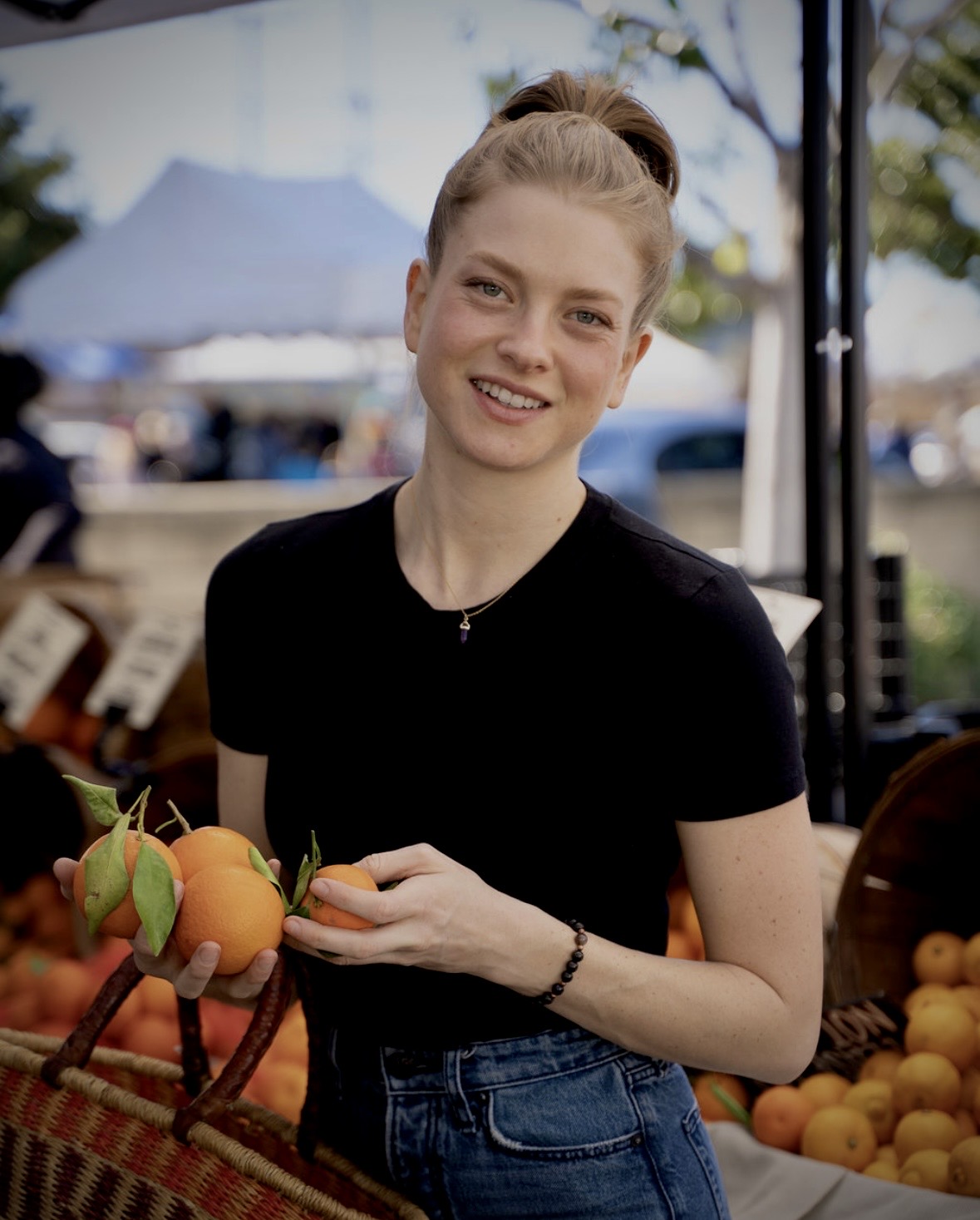Shayna smiling at a farmers market holding fresh oranges