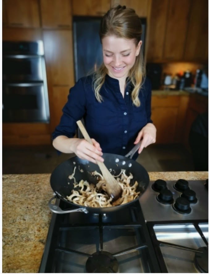Shayna cooking in the kitchen, sautéing in a wok